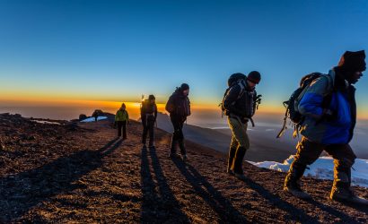 Trekkers walking along the Kilimanjaro crater rim at sunrise on summit day